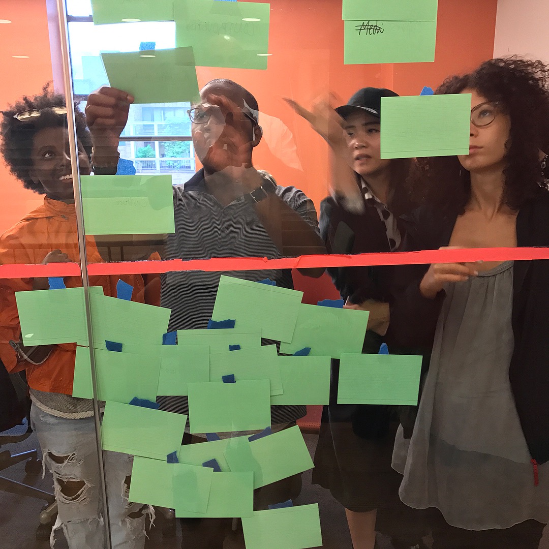 Four Arts Politics students put up green notecards on clear glass wall
